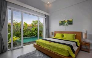 a bedroom with a green bed and a large window at Gemello Bali Villa in Keramas +41 photos