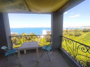 a balcony with a table and chairs and the ocean at Pinwheel Hostel Vlora & Rooftop Bar in Vlorë