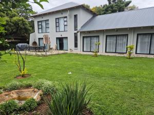 a white house with a yard with a lawn sidx sidx sidx at Comfort Cove in Pretoria