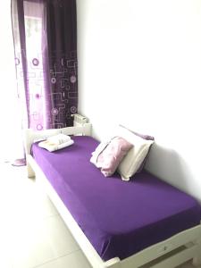 uma cama com lençóis e almofadas roxos num quarto em Toco el Cielo Aparts em Tigre