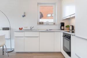 a white kitchen with a sink and a window at Strandlächeln in Neue Tiefe Fehmarn