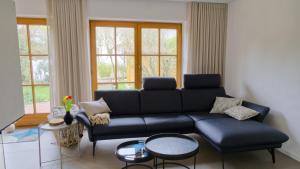 a living room with a black couch and windows at Ferienhaus Mind-Storm in Rimsting