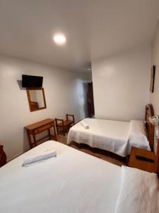 a hotel room with two beds and a television at Hostal Los Amigos in Olivenza
