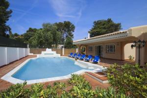 a swimming pool with blue chairs and a house at Spacious Private Villa with Pool in Salou in Salou
