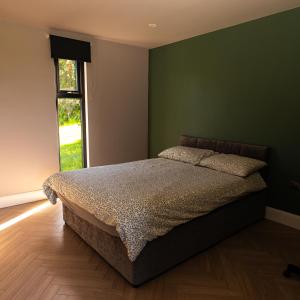 a bedroom with a bed with a green wall at Wild Atlantic Camp in Creeslough