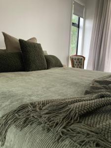 a bed with a gray blanket and pillows on it at The Batch in Oamaru