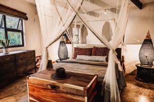 a bedroom with a canopy bed with a hat on a table at Chobe House Villa and Chalets in Kasane