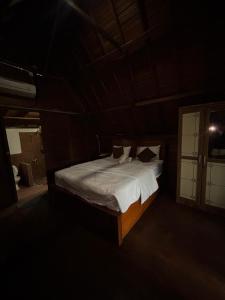 a bedroom with a bed with white sheets and pillows at KRECOG Bungalow in Sampalan
