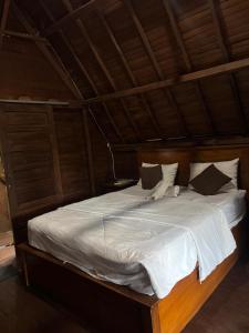 a large bed with white sheets and pillows at KRECOG Bungalow in Sampalan