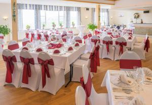 a banquet hall with white tables and red bows at Hotel Restaurant Bergeshöhe in Mettingen