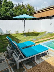 a pair of lounge chairs and an umbrella next to a pool at Villa Le Caprice in Grand-Baie