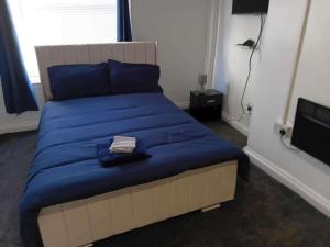 a bed with blue sheets and blue pillows in a room at Sleeps 2 - Parking - Wifi in Oldbury