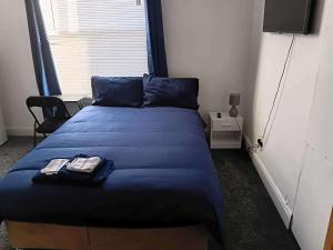 a bedroom with a bed with blue sheets and a television at Sleeps 2 - Parking - Wifi in Oldbury