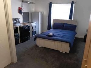a bedroom with a bed with blue sheets and a kitchen at Sleeps 2 - Parking - Wifi in Oldbury