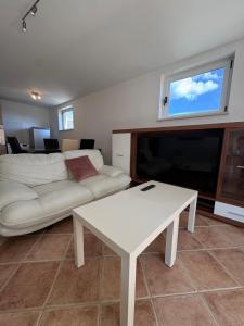 a living room with a white couch and a tv at Central nude oasis in Makarska