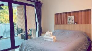 a bedroom with a bed with towels and a balcony at My Home Villa Phangnga in Phangnga