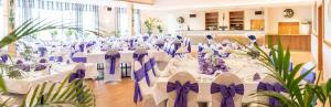a banquet hall with white tables and purple chairs at Hotel Restaurant Bergeshöhe in Mettingen