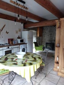 a kitchen with a table and a stove and a refrigerator at Le fourezon in Saint-Jeures