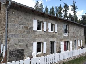 a brick building with white windows and a white fence at Le fourezon in Saint-Jeures