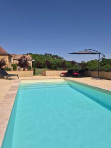 a large blue swimming pool with an umbrella at Le Bos Dordogne in Soulaures