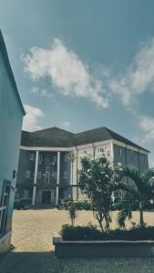 a large building with palm trees in front of it at Davic-lite hotel and suites in Okitipupa