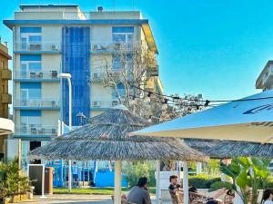 a group of people sitting under umbrellas in front of a building at Hotel Degli Angeli Riccione in Riccione
