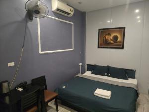 a bedroom with a green bed with a fan at Gia An Hotel in Hanoi +2 photos