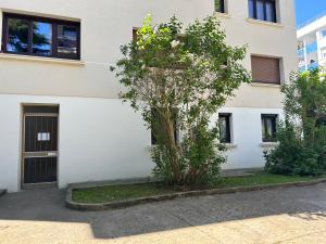 a white building with a tree in front of it at Studio cosy et calme à Garches in Garches