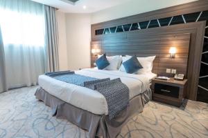 a bedroom with a large bed with a wooden headboard at Corniche Hotel Al Khobar in Al Khobar