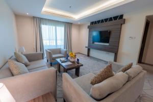 a living room with two couches and a tv at Corniche Hotel Al Khobar in Al Khobar