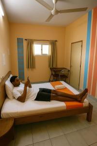 a man laying on a bed in a bedroom at L'Hotel 5-5 in Mahajanga