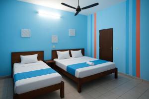 a room with two beds and a blue wall at L'Hotel 5-5 in Mahajanga