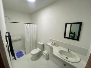 a white bathroom with a toilet and a sink at Fauna in Santa Marta
