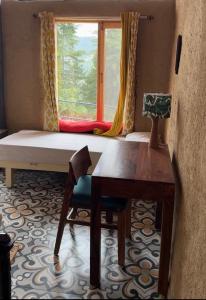 a room with a bed and a desk and a window at Nomad Eco Retreat in Shimla