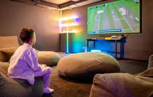 a young boy sitting on a couch watching a tv at Dunetton - self check-in hotel in Klaipėda