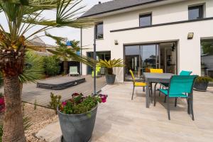 a patio with a table and chairs and a palm tree at Chambre d'hôtes reflets du Golfe in Arradon
