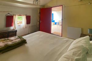 a bedroom with a white bed and a red door at Casa no Campo in Porto Covo