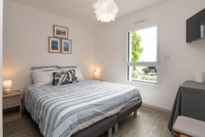 a white bedroom with a bed and a window at Chambre d'hôtes reflets du Golfe in Arradon
