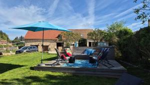 a patio with two chairs and an umbrella at Le figuier in Benayes