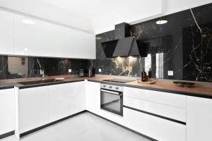 a kitchen with white cabinets and black marble walls at Lambda Luxury Villa 2 in Syvota