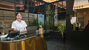 a woman standing behind a desk with a laptop at The SACHA Apart-Hotel Thonglor Sukhumvit Bangkok in Bangkok +79 photos