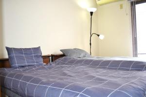 a bed with a blue comforter in a bedroom at ビレッジ幸 in Otsu