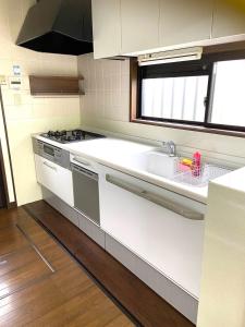 a white kitchen with a sink and a stove at ビレッジ幸 in Otsu