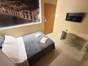 a bedroom with a bed and a desk and a television at Studios 138 in Belém