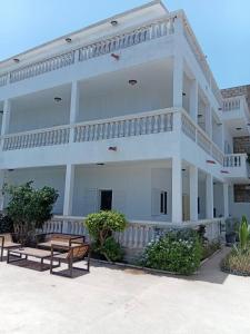 a white building with benches in front of it at New White House in Saly Portudal