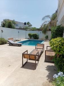 a swimming pool with three benches next to a building at New White House in Saly Portudal
