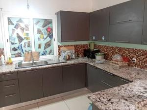 a kitchen with brown cabinets and a sink and a window at New White House in Saly Portudal