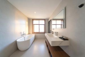 ein Badezimmer mit einer großen weißen Badewanne und einem Waschbecken in der Unterkunft Zhangjiajie JOY Hotel -New Hotel ,Avatar Mountain View, Walking Distance to the Middle Gate of Forest Park,Quite Entrance, Less Crowed & No Queue,Free well-prepared Breakfast,Free Self-Service Laundry & Drying, Attraction Tickets Serivce,Nice Host in Zhangjiajie