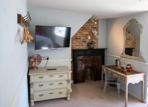 a room with a fireplace and a desk and a television at The Woolpack Hotel in Tenterden