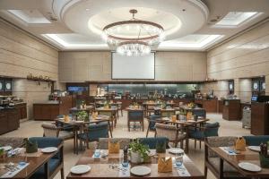 a restaurant with tables and chairs and a projection screen at Grand Mercure Vadodara Surya Palace in Vadodara